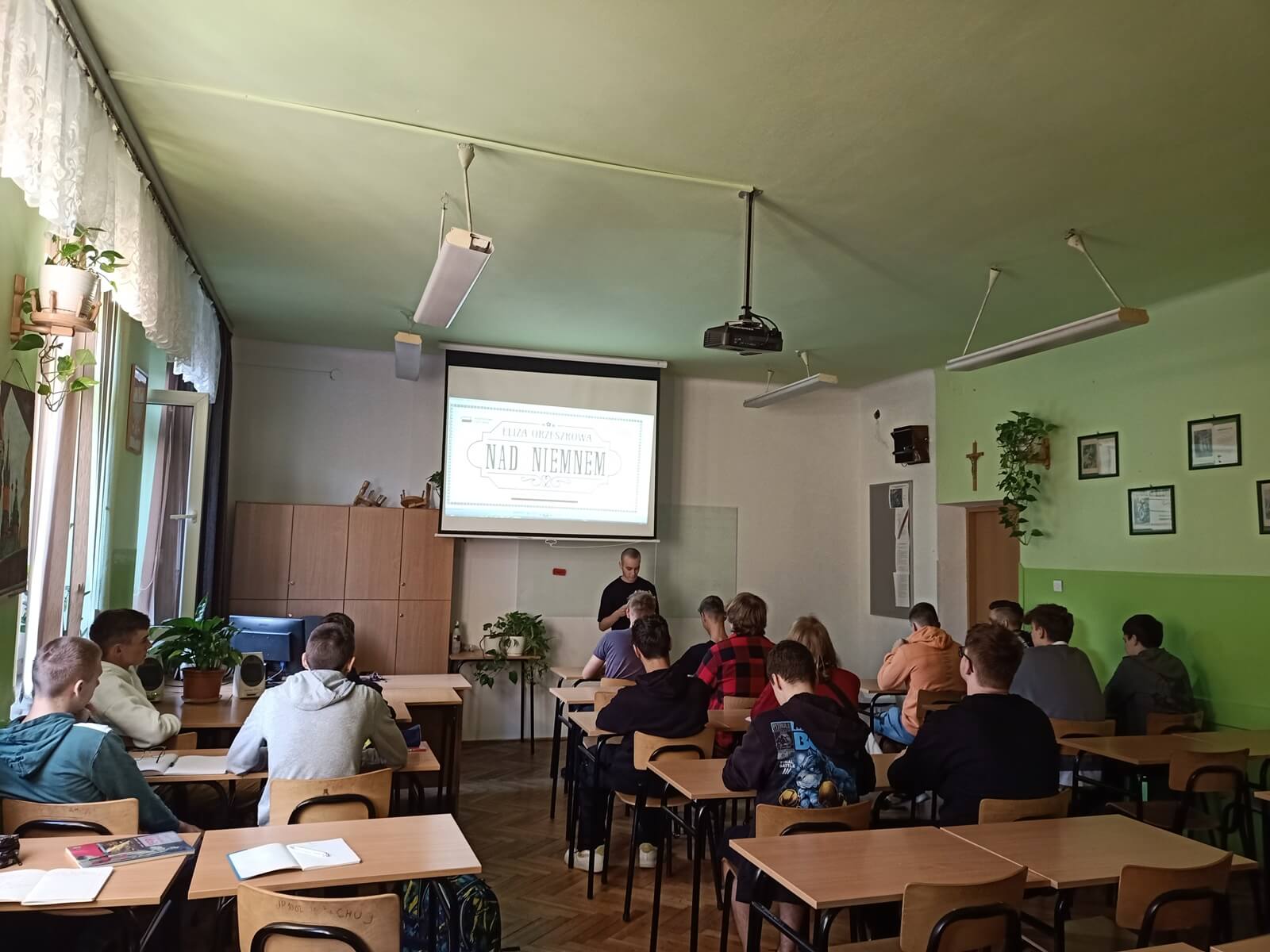 sala lekcyjna. W tle uczeń czytający książkę