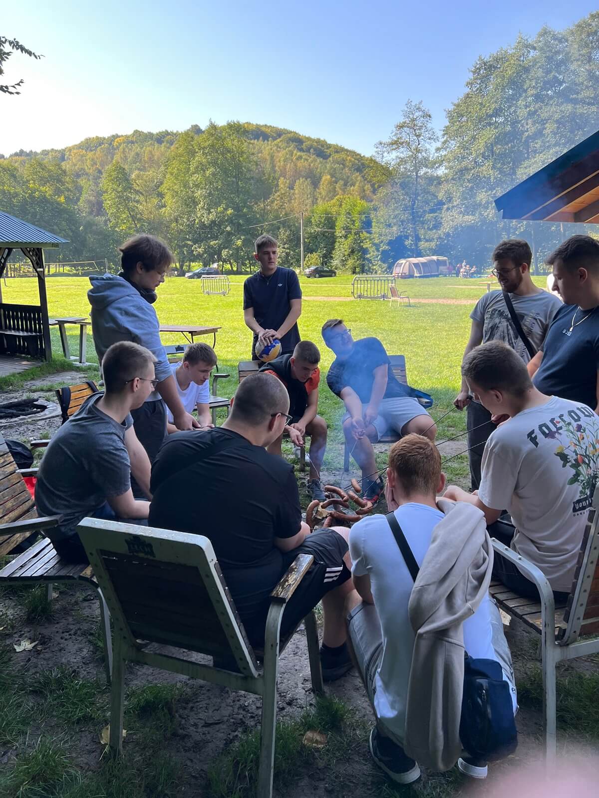 grupa uczniów siedzi wokół ogniska