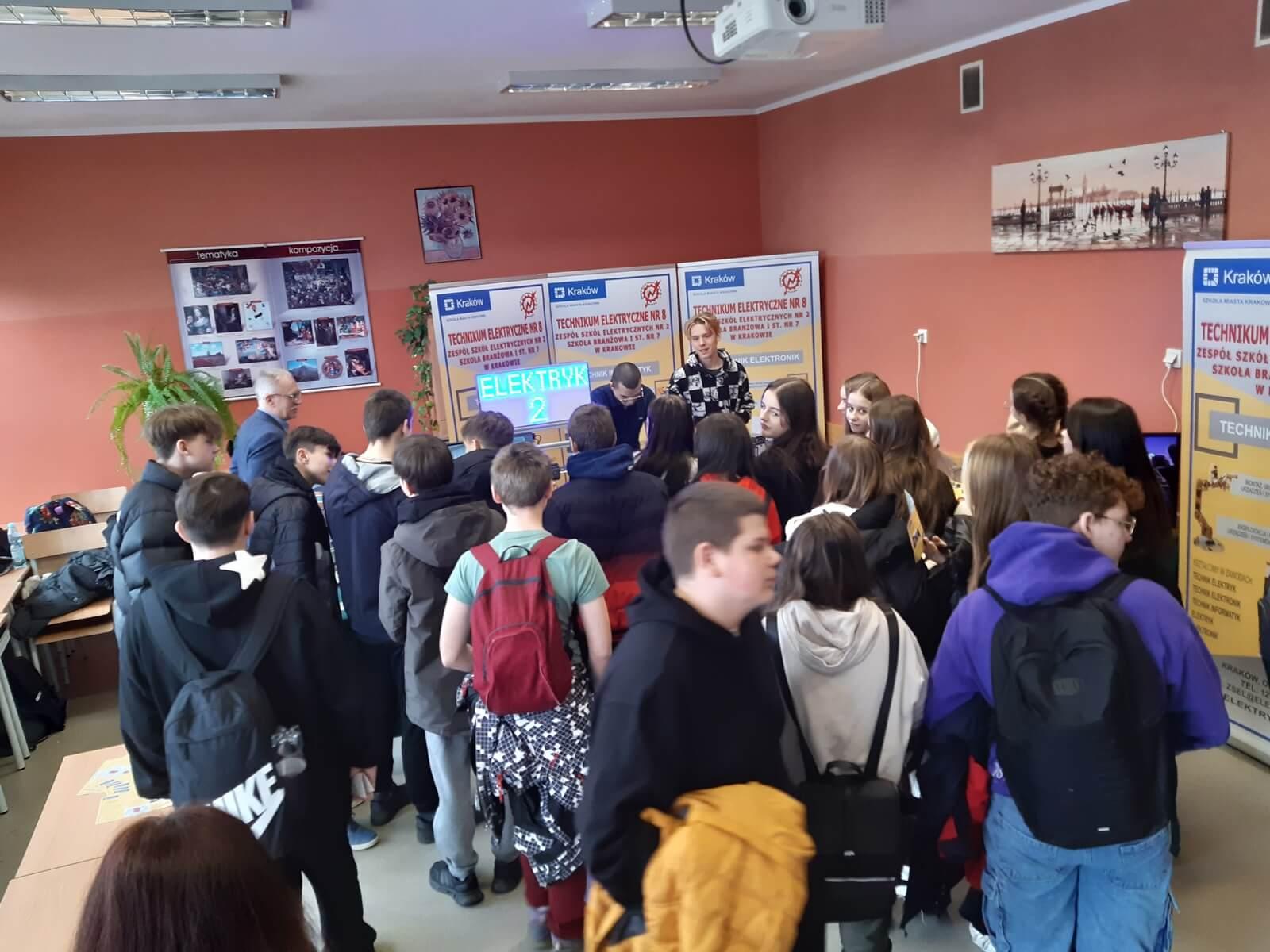 Grupa uczniów odwiedzających stoisko z prezentacja oferty edukacyjnej naszej szkoły.